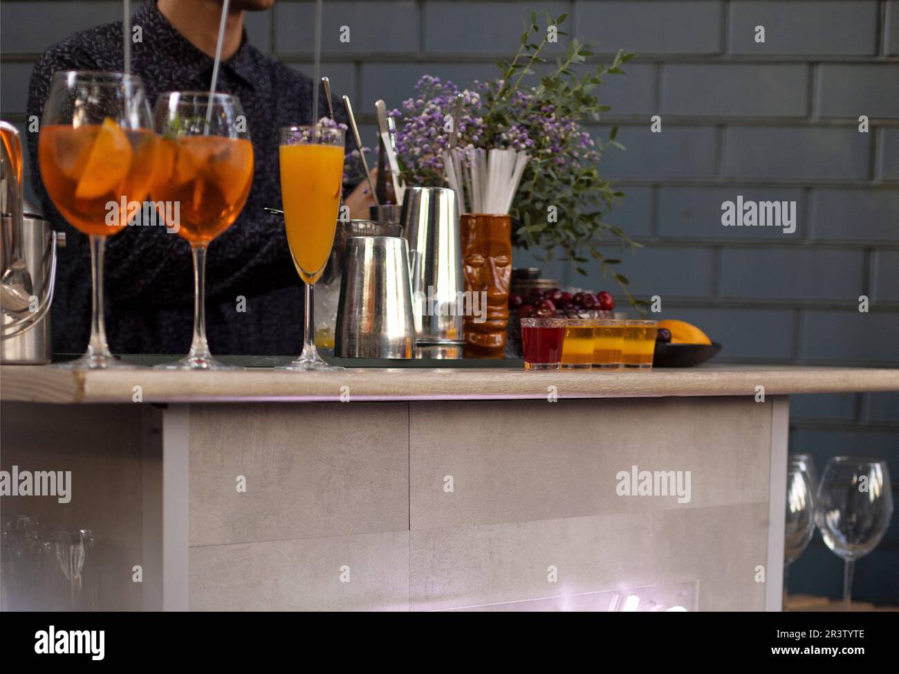 Gläser Cocktails an der Bar. Der Barkeeper schenkt ein Glas Sekt mit rotem Alkohol ein. Stockfoto