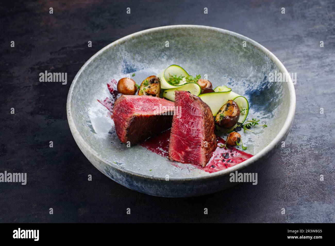 Gebratenes italienisches chianina-Rinderfilet sehr selten mit Pilzen, Zucchini und Amarena-Sauce, serviert aus nächster Nähe in einer Schüssel im nordischen Design Stockfoto