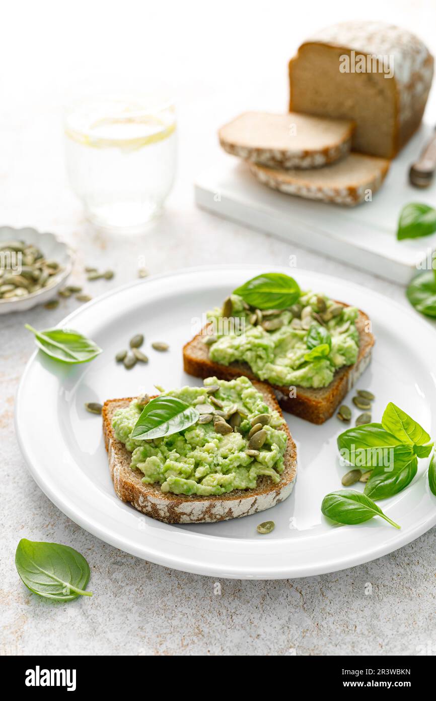 Avocado-Sandwich mit Kürbiskernen. Gesunder vegetarischer Avocado Toast mit Roggenbrot zum Frühstück. Vegane Speisekarte Stockfoto