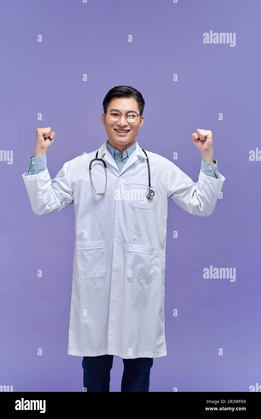 Junger asiatischer Arzt, der nach einem Sieg die Faust erhebt, Siegerkonzept. Stockfoto