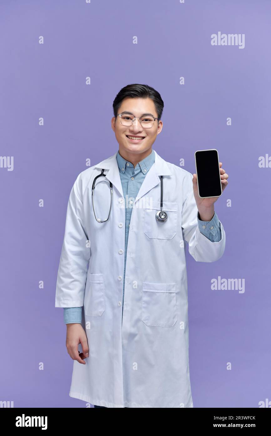 Ein männlicher Arzt trägt ein Stethoskop, zeigt ein leeres Handy-Display Stockfoto