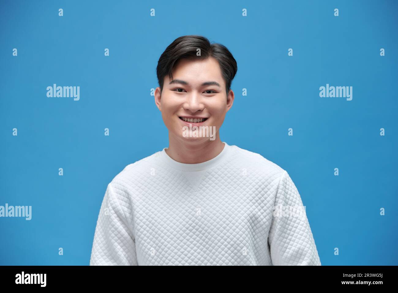 Porträt eines glücklichen Asiaten im weißen T-Shirt auf isoliertem blauem Hintergrund. Stockfoto