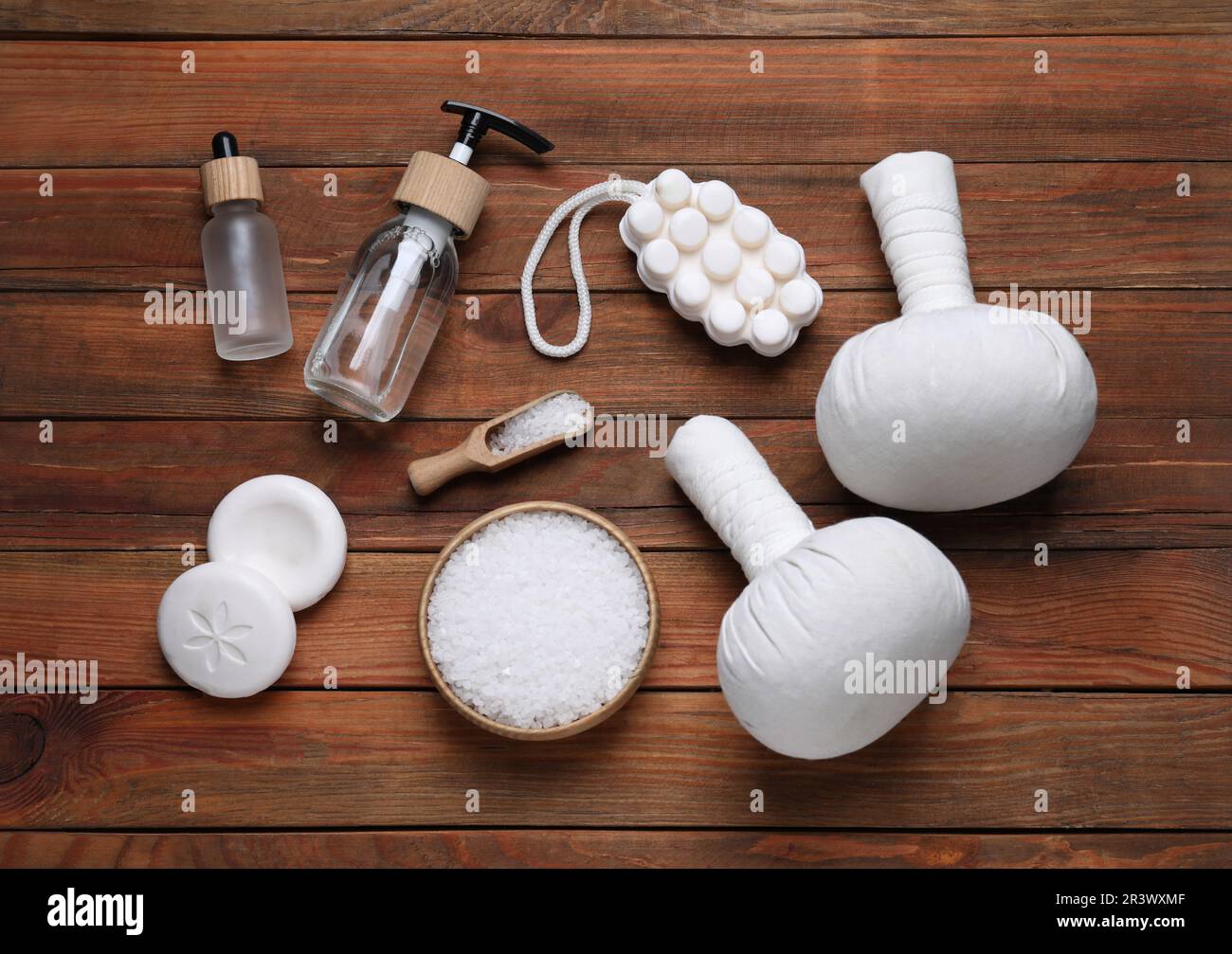 Flache Laienzusammensetzung von Kräuterbeuteln und Spa-Produkten auf Holztisch Stockfoto