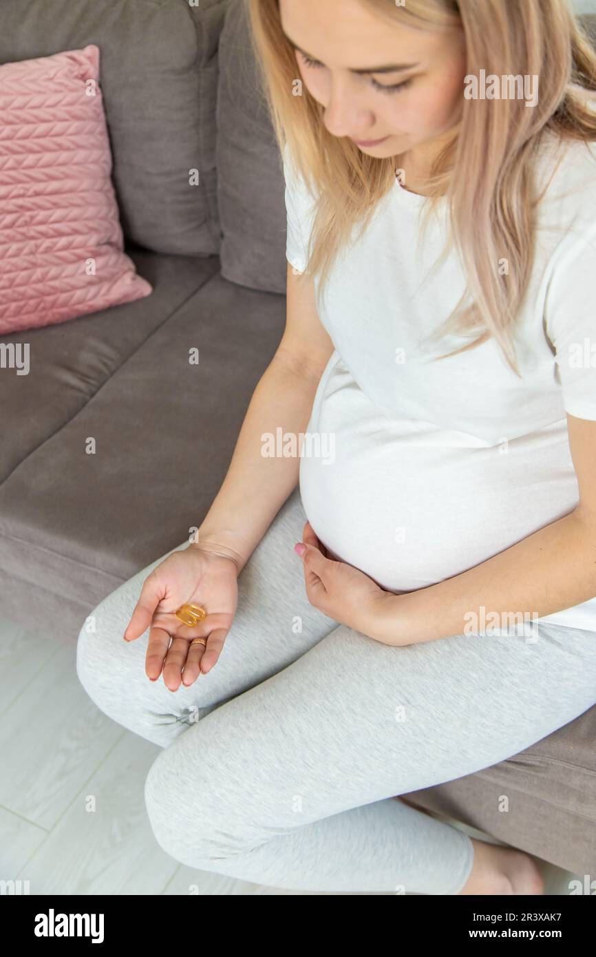 Schwangere Frau trinkt Omega drei. Selektiver Fokus. Weiß. Stockfoto