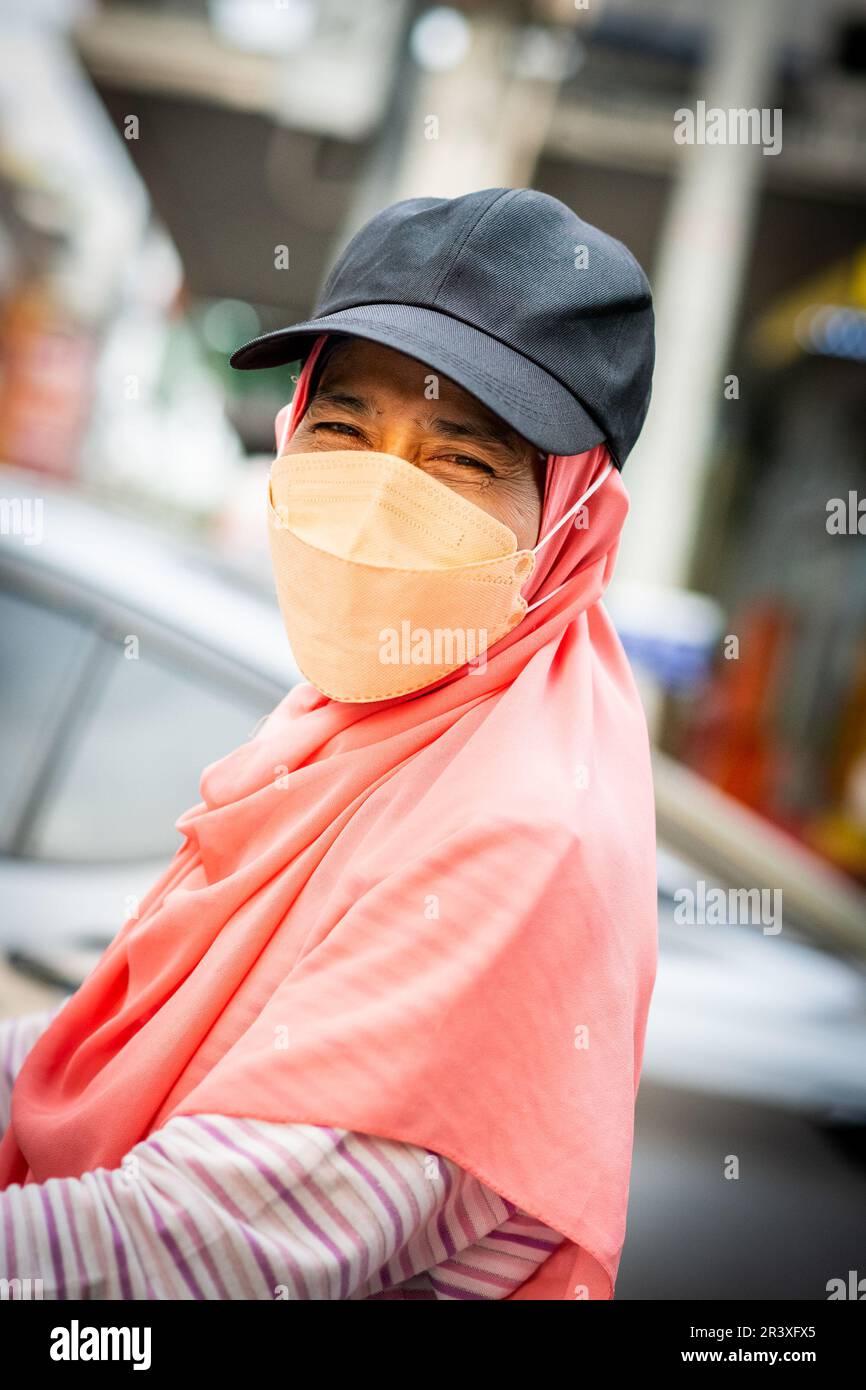 Eine thailändische Dame, die eine Maske trägt, um sich vor Verschmutzung zu schützen, und Covid wirft ein Lächeln auf Soi Buakhao in Pattaya Thailand. Stockfoto