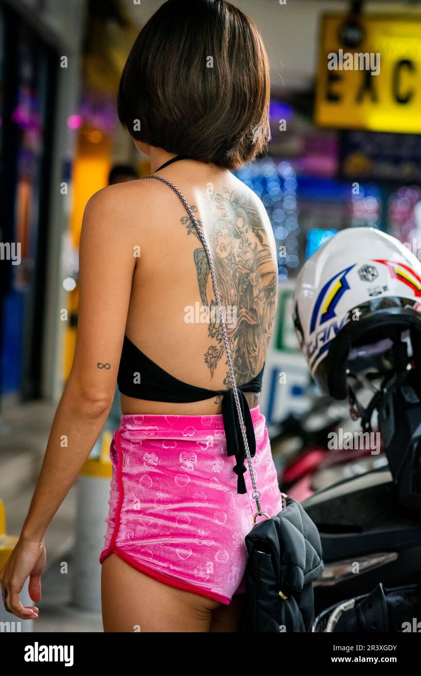 Eine wunderschöne junge thailändische Dame mit einem atemberaubenden Tattoo macht sich auf dem Soi Buakhao in Pattaya Thailand auf den Weg ins Jahr 7-11. Stockfoto