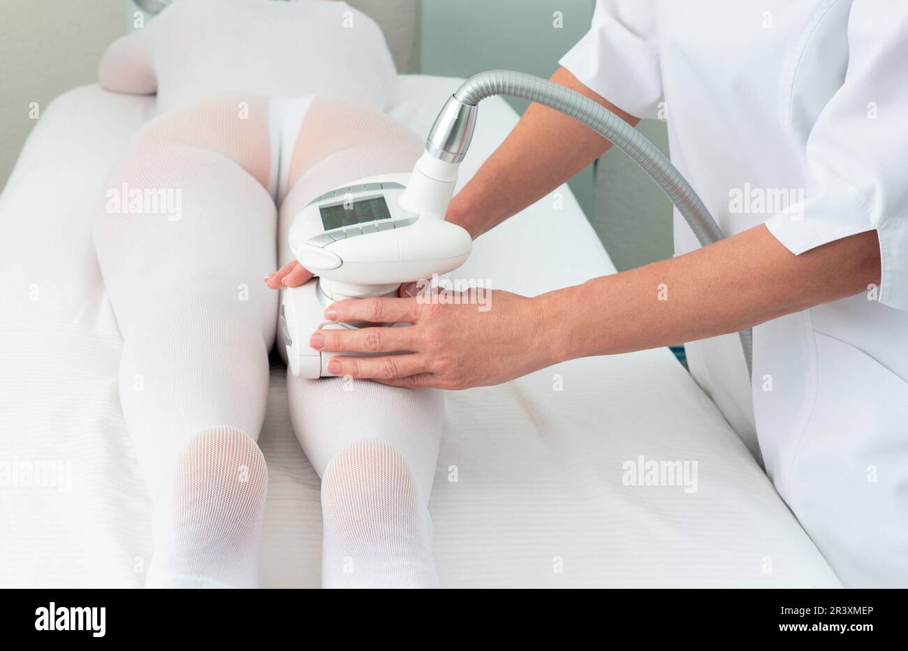 Eine Frau in einem speziellen weißen Anzug bekommt eine Anti-Cellulite-Massage für die Beine in einem Spa-Salon. LPG und Körperkonturierungsbehandlung in der Klinik Stockfoto