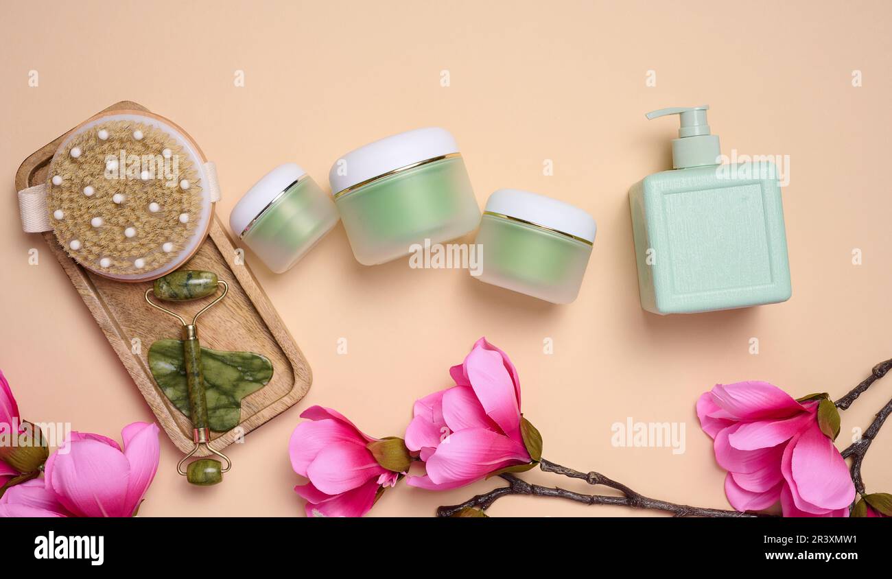 Grüne Kosmetikbecher aus Kunststoff, Massagegerät aus Stein und Holzbürste. Schönheitsbehandlungsmittel Stockfoto