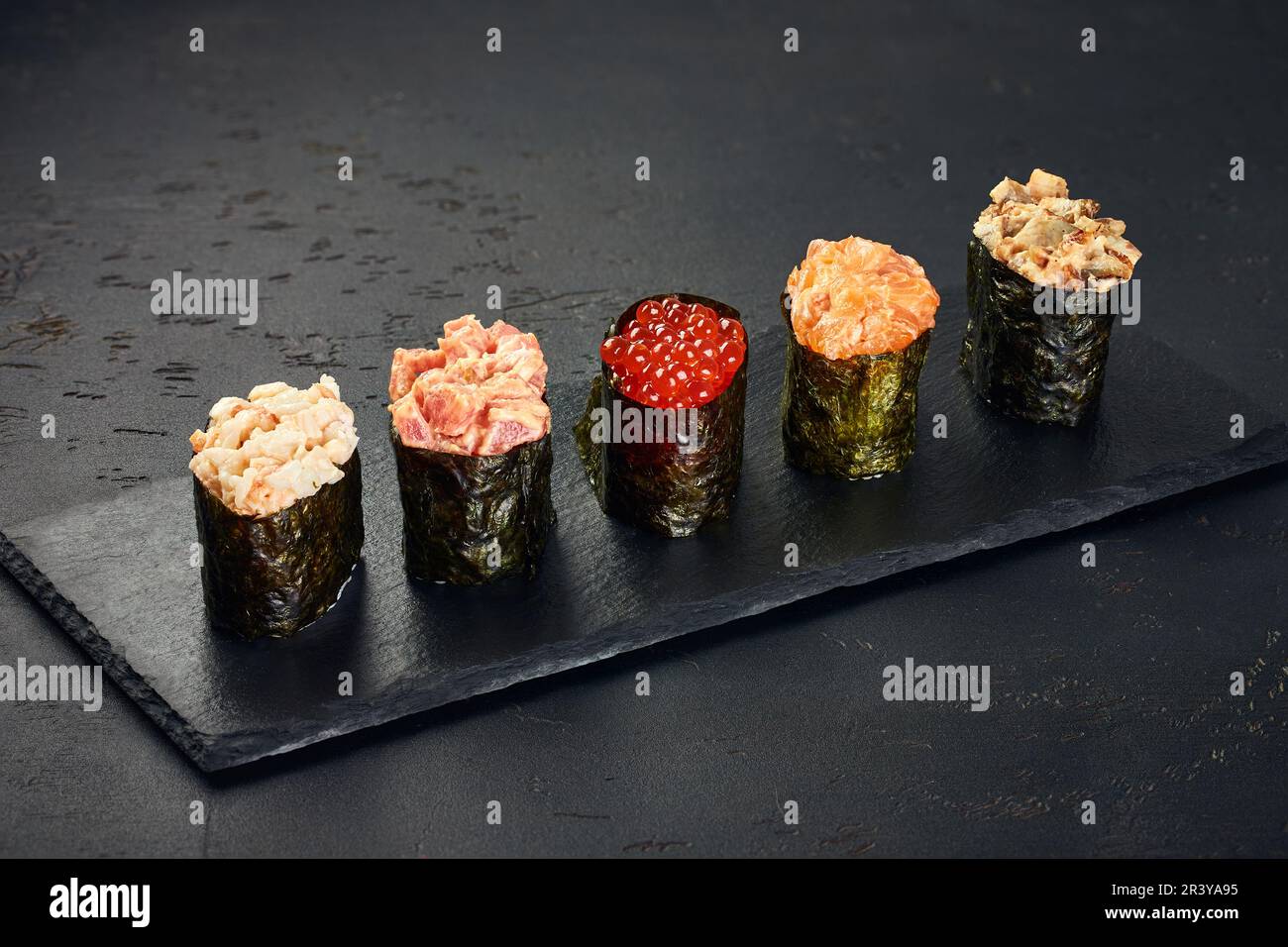 Set aus Gunkan Maki Sushi mit verschiedenen Arten von Fisch (Lachs, Jakobsmuscheln, Barsch, Aal, Garnelen) und Kaviar auf schwarzem Hintergrund. Trad Stockfoto