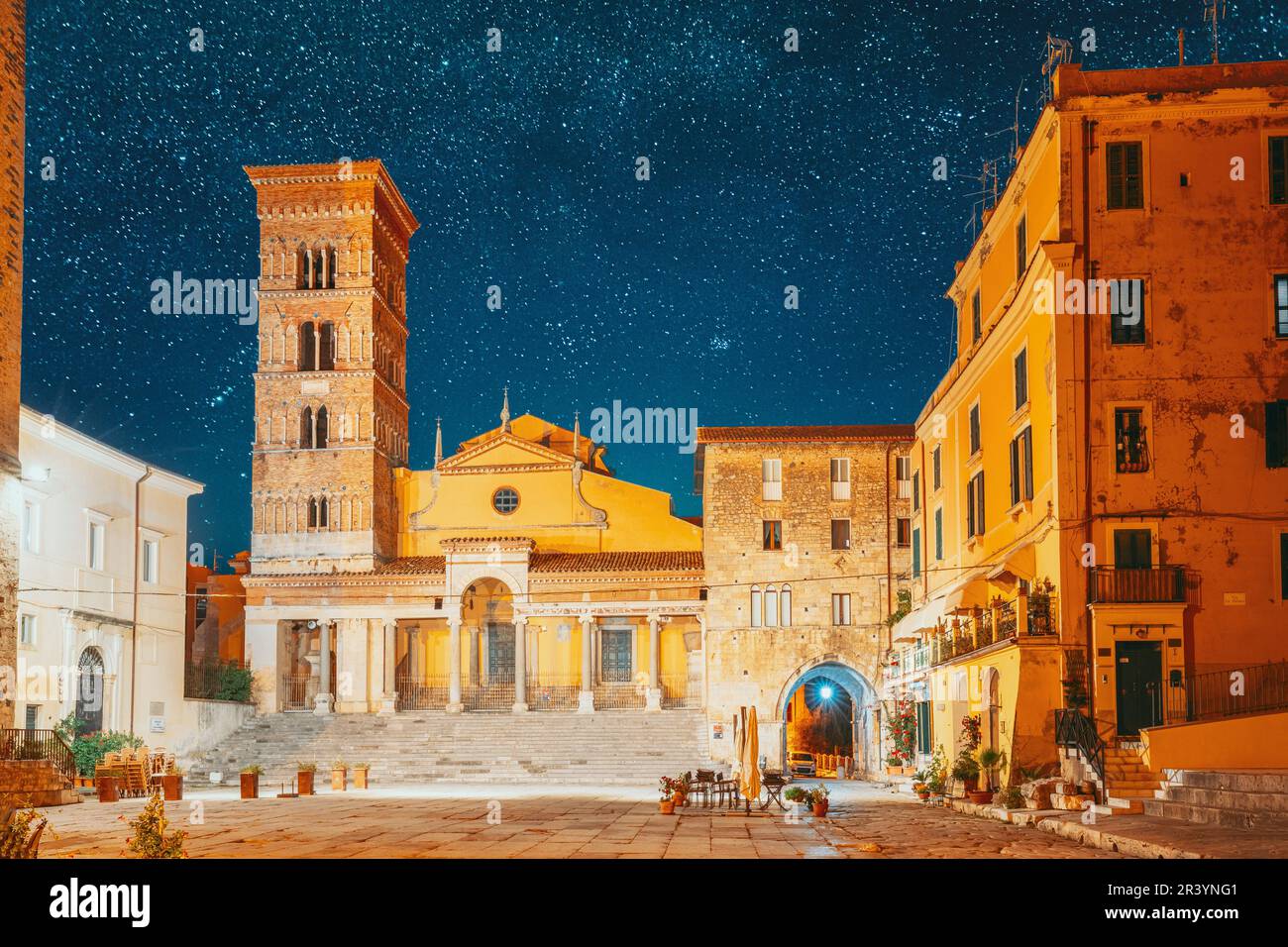 Terracina, Italien. Leuchtender Blauer Sternenhimmel Mit Leuchtenden Sternen Über Dem Turm Der Kathedrale Von San Cesareo Bei Nacht. Es Wurde Auf Dem Podium Von Gebaut Stockfoto