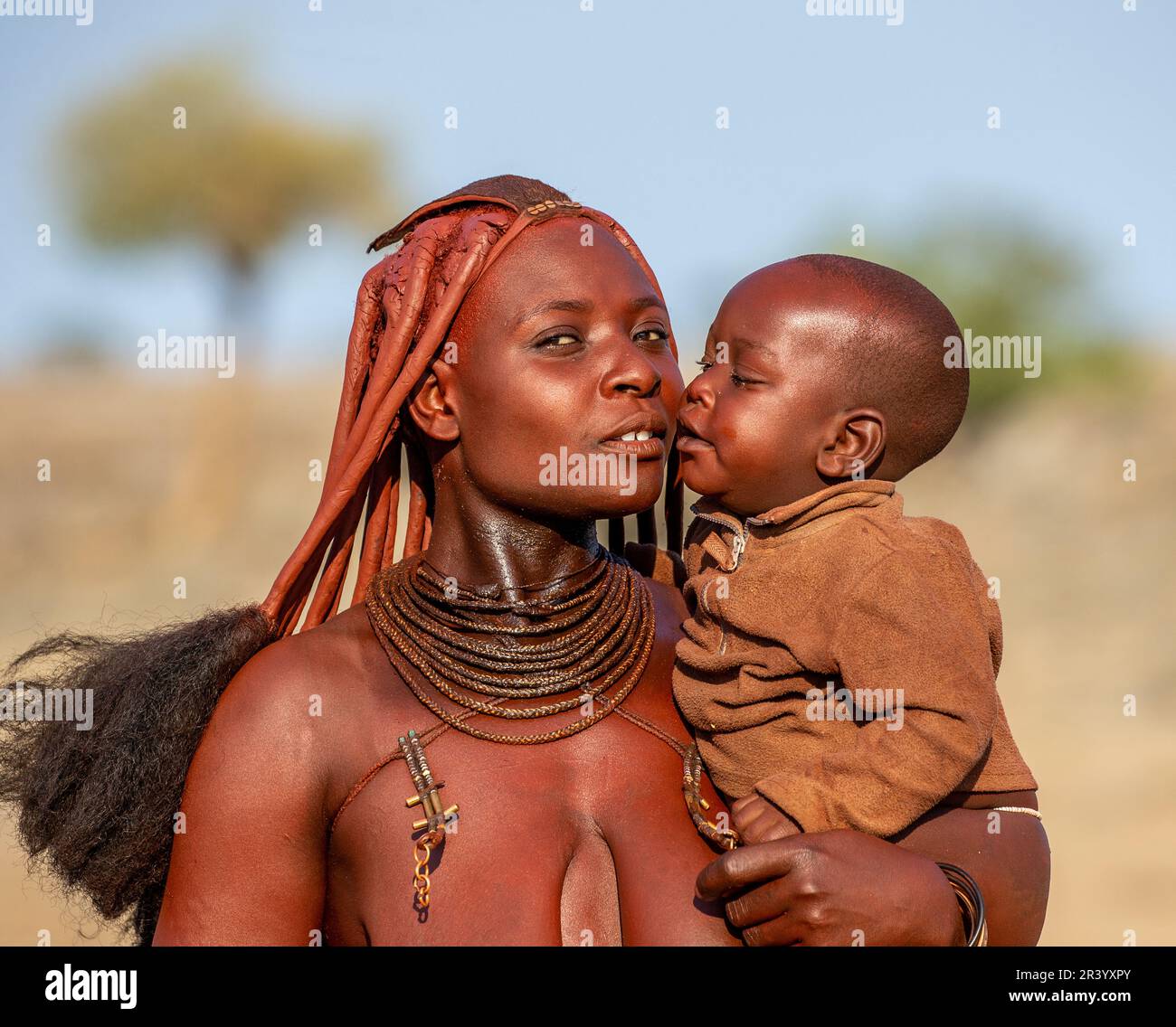 Porträt einer jungen Frau des Himba-Stammes mit einem kleinen Kind in ihren Armen. Stockfoto