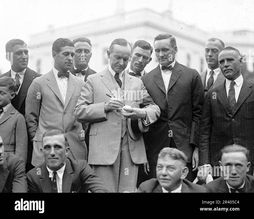 President Calvin Coolidge signs a baseball for Hall of Fame pitcher Walter Johnson as other members of the Senators look on in 1924. (Library of Congress via AP) Stockfoto