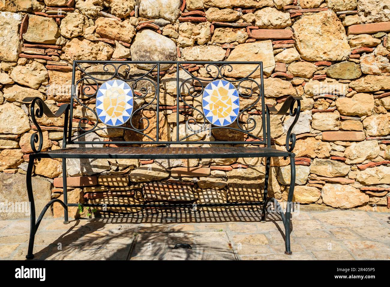 Malerische Bank aus Metall mit heller sandfarbener Wand Stockfoto