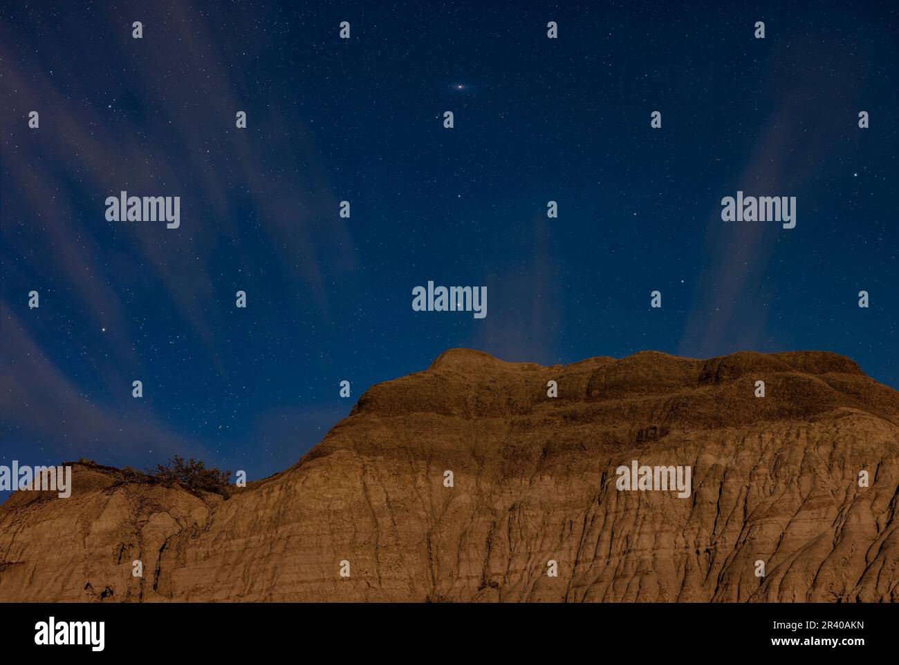 Die Andromeda Galaxy und die Sterne erheben sich über mondbeleuchteten Hoodoo-Formationen im Dinosaur Provincial Park. Stockfoto