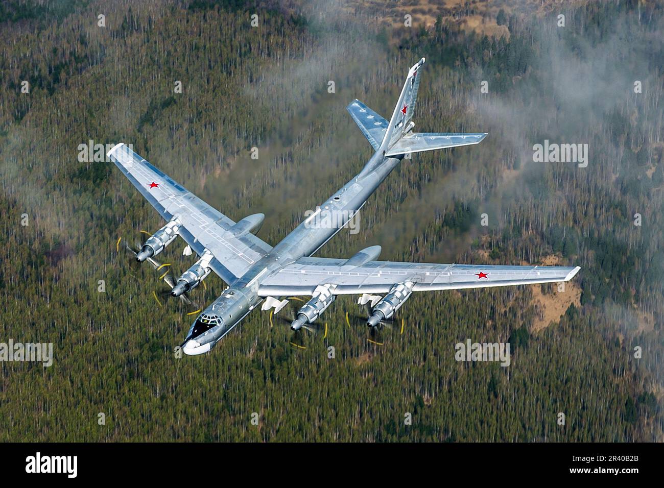 Ein strategischer TU-95MS-Bomber der russischen Luftwaffe, der über einen Wald von Bäumen in Russland fliegt. Stockfoto