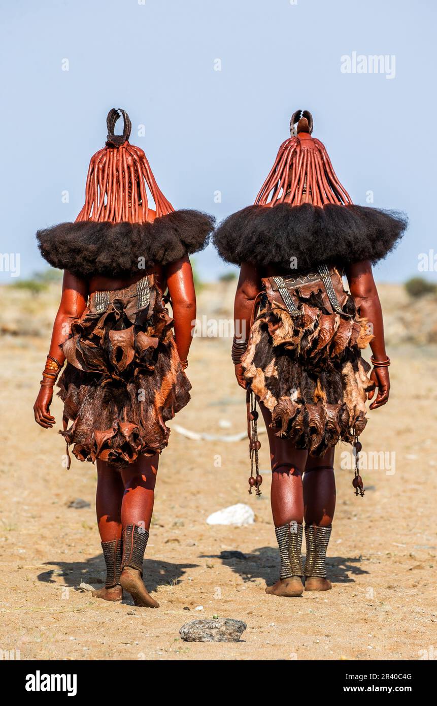 Zwei Frauen des Himba-Stammes laufen in Nationalkleidung durch die Wüste. Stockfoto