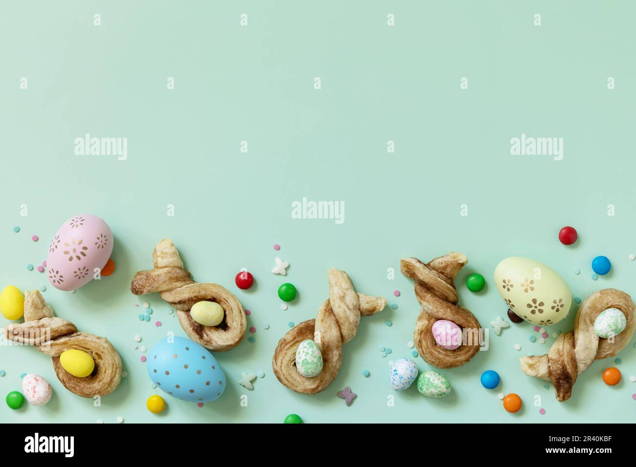 Färbt Ostereier mit Kaninchenbrötchen in Osterform mit Zimt auf pastellgrünem Hintergrund. Frohe Osterferien. V Stockfoto