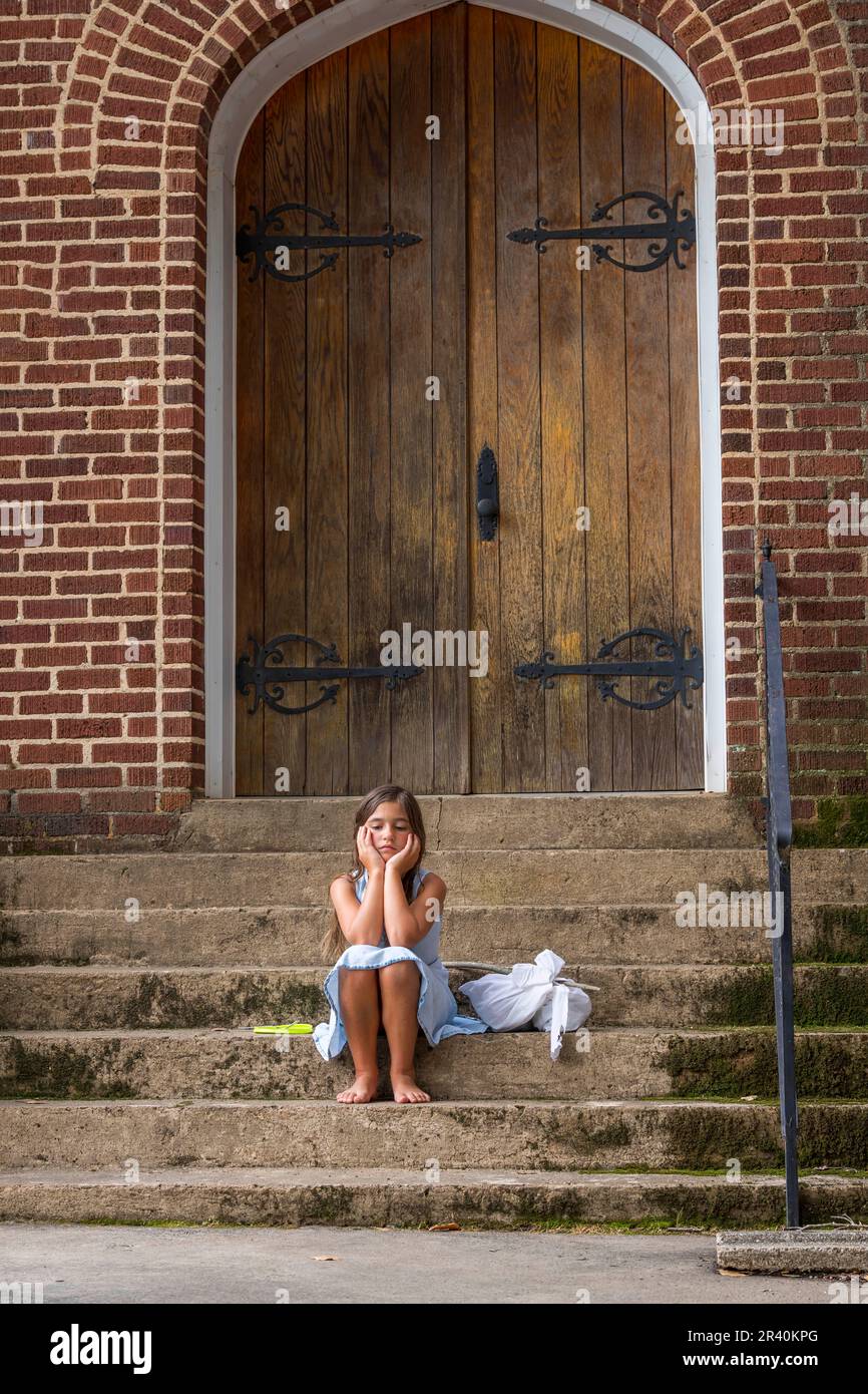 Ein hungriges, obdachloses, verlassenes Kind sucht vor Einer Kirche nach Nahrung und Unterkunft Stockfoto