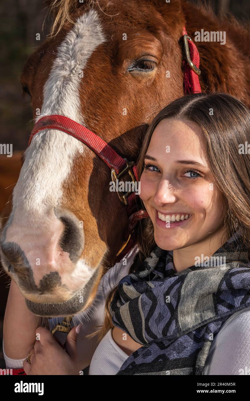 Hübsches braunes Cowgirl, das einen Tag mit ihrem Pferd auf der Farm genießt Stockfoto