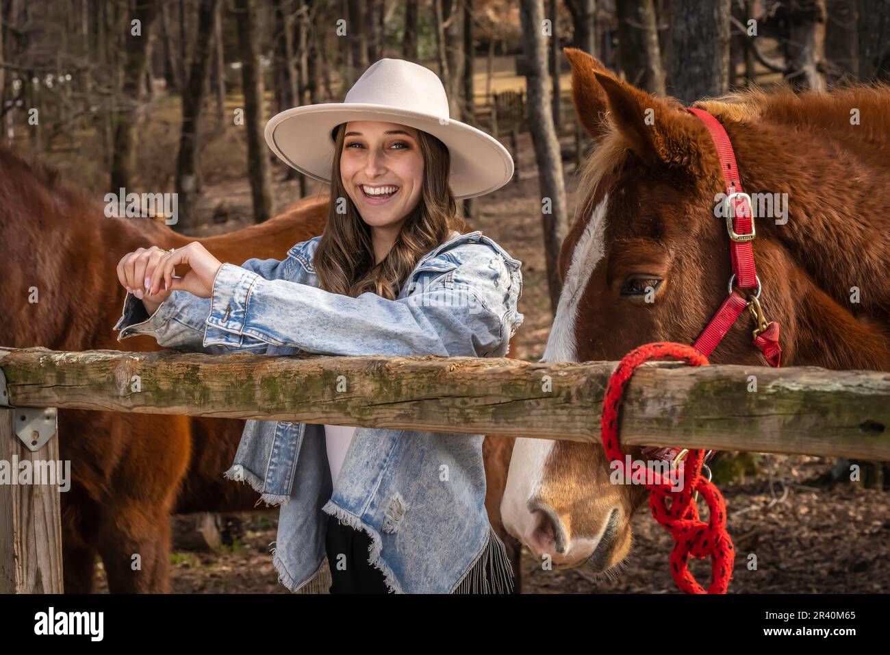 Hübsches braunes Cowgirl, das einen Tag mit ihrem Pferd auf der Farm genießt Stockfoto