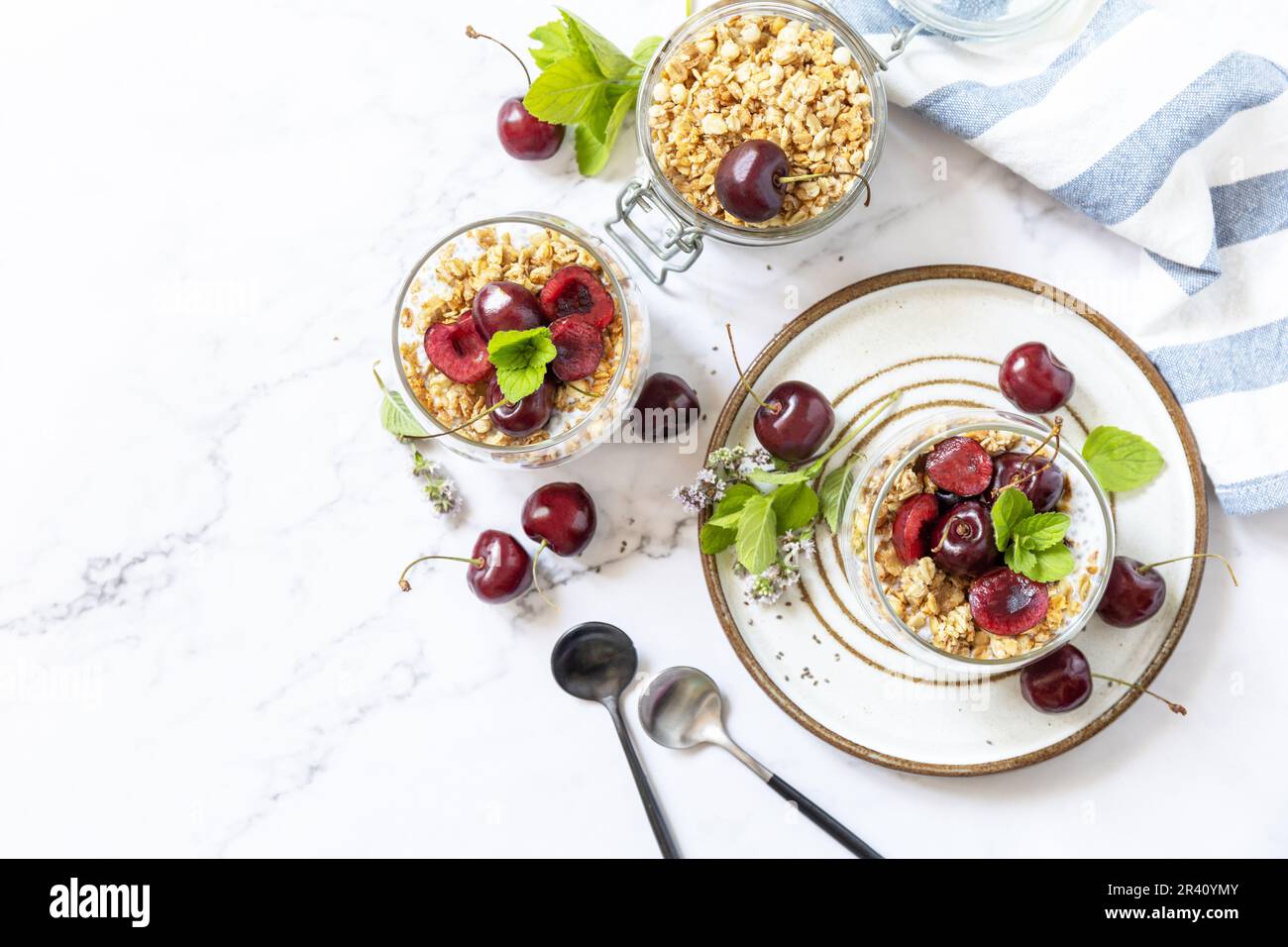 Gesundes Menü-Konzept. Hausgemachtes Müsli-Frühstück. Ein Glas Parfait aus Müsli, Beeren, Kirsche, Joghurt mit Chiasamen auf r. Stockfoto