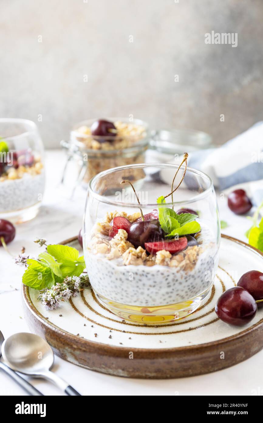 Gesundes Menü-Konzept. Hausgemachtes Müsli-Frühstück. Ein Glas Parfait aus Müsli, Beeren, Kirsche, Joghurt mit Chiasamen auf r. Stockfoto