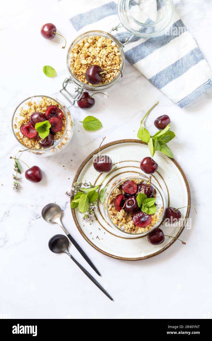 Gesundes Menü-Konzept. Hausgemachtes Müsli-Frühstück. Ein Glas Parfait aus Müsli, Beeren, Kirsche, Joghurt mit Chiasamen auf r. Stockfoto