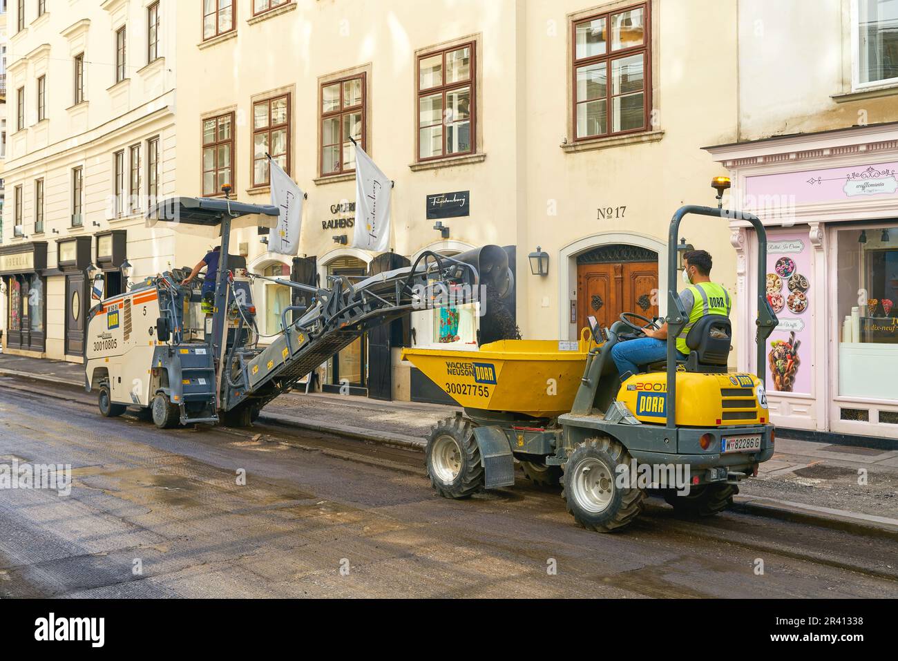 Arbeiter im Zentrum von Wien arbeiten beim Fräsen, um den Asphalt einer Straße zu erneuern Stockfoto