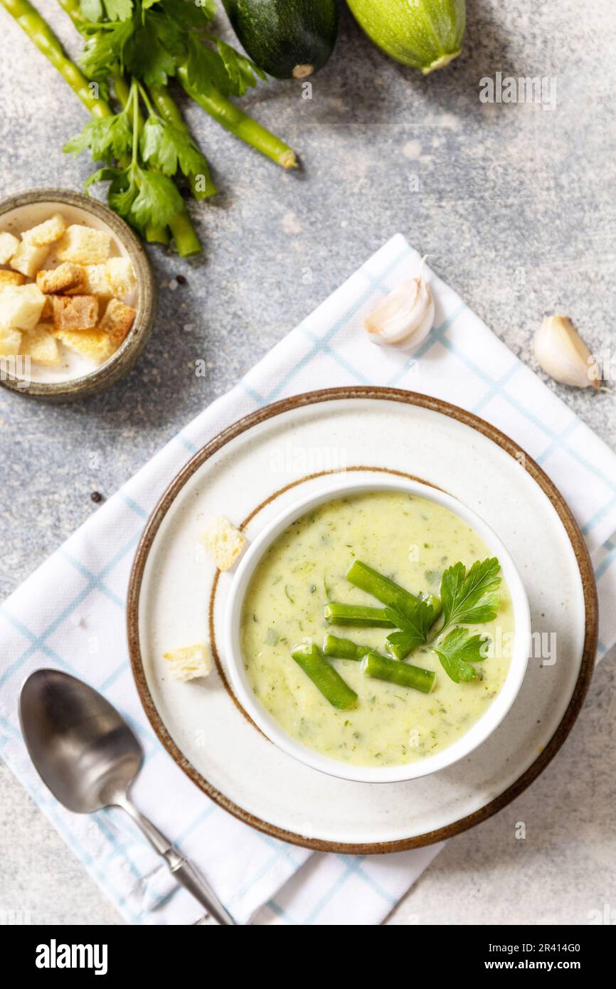 Gesundes Essen. Vegane Suppenpüree aus grünem Gemüse. Schüssel mit grüner Bohne und Zucchini-Sahne-Suppe auf einem Steintisch. Blick von oben Stockfoto