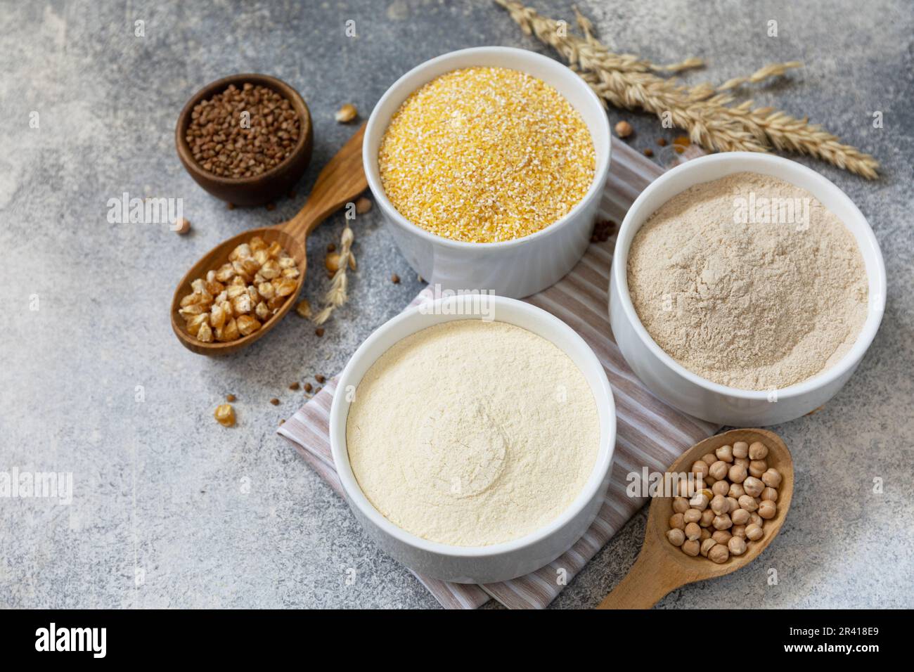 Lebensmittel und glutenfreie Backzutat. Getreide und Mehl grob, Maismehl, Buchweizenmehl, Kichererbsenmehl über grauem Stein Stockfoto