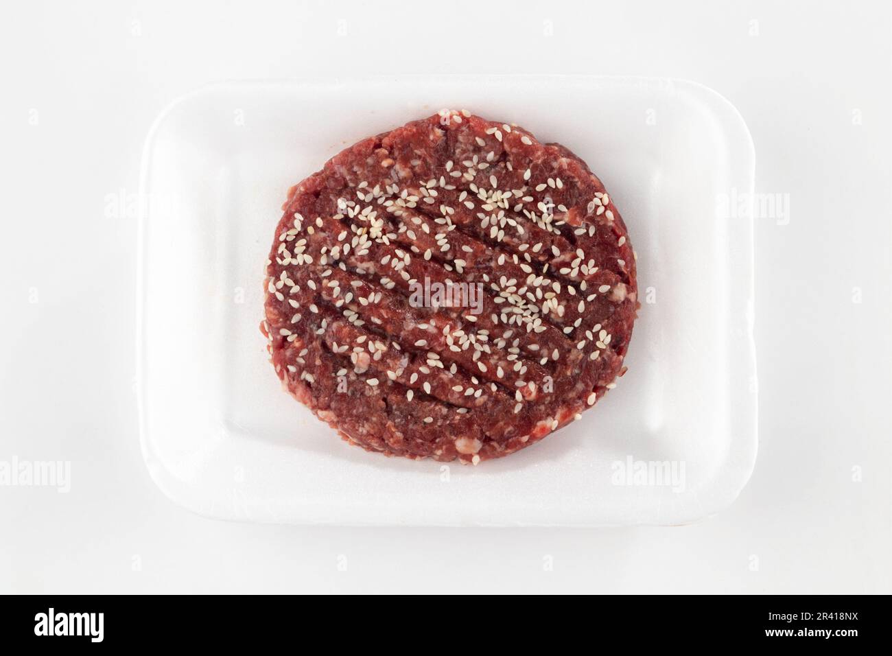 Rohe Hamburger-Pasteten mit Sesamsamen, isoliert auf weißem Hintergrund Stockfoto