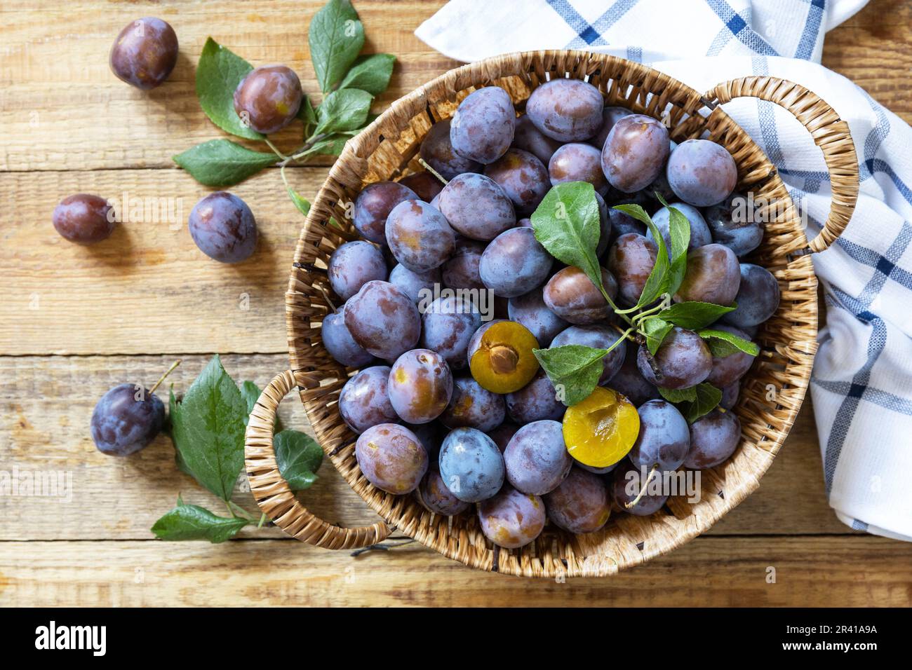 Obst Hintergrund, Bio-Früchte. Stillleben Essen. Korb mit frischen blauen Pflaumen auf einem rustikalen Holztisch. Blick von oben. Stockfoto