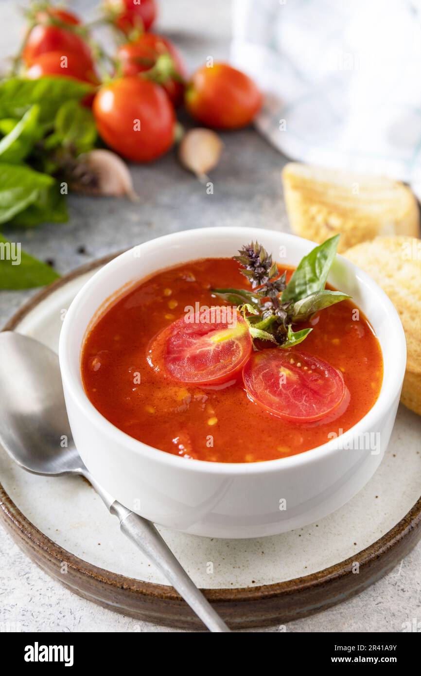 Vegane Suppenpüree Tomaten. Vegetarische gesunde Ernährung. Schüssel Tomatensuppe mit Basilikum und Croutons auf einem Steintisch. Stockfoto