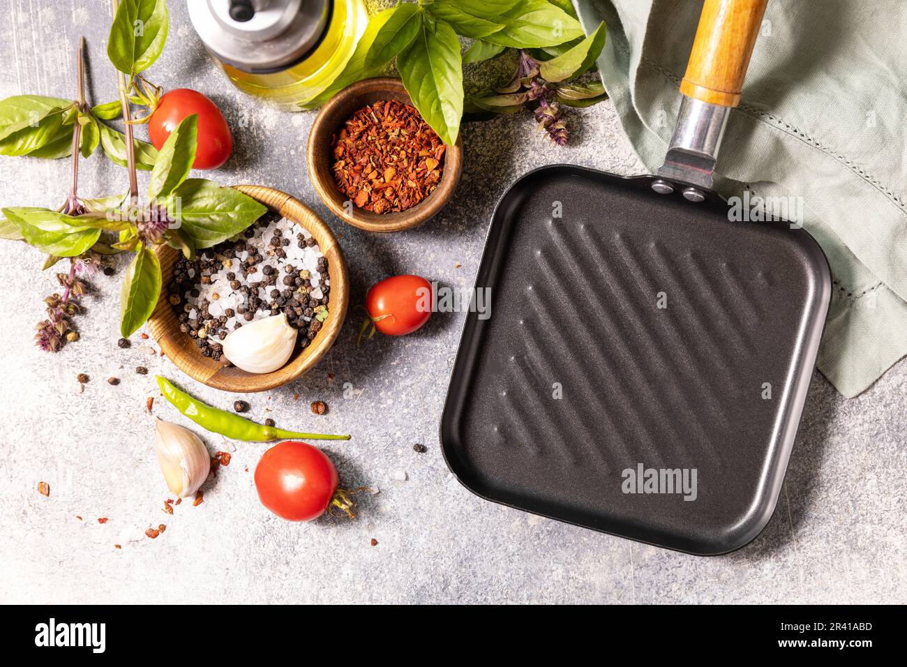 Kochhintergrund auf grauem Hintergrund mit Grillpfanne. Leere Grillpfanne, Gemüse, Gewürze und Kräuter auf einem Steintisch. Vi Stockfoto
