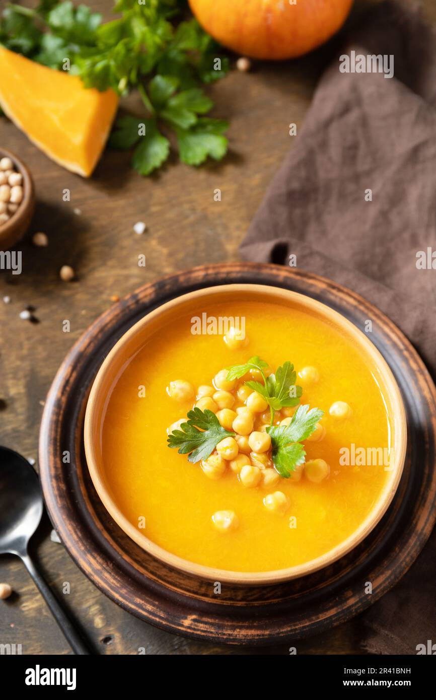 Comfort Food, Herbst und Winter gesundes Slow Food Konzept. Vegetarische Kürbis- und Kichererbsencremesuppe auf einem rustikalen Holztisch. Stockfoto