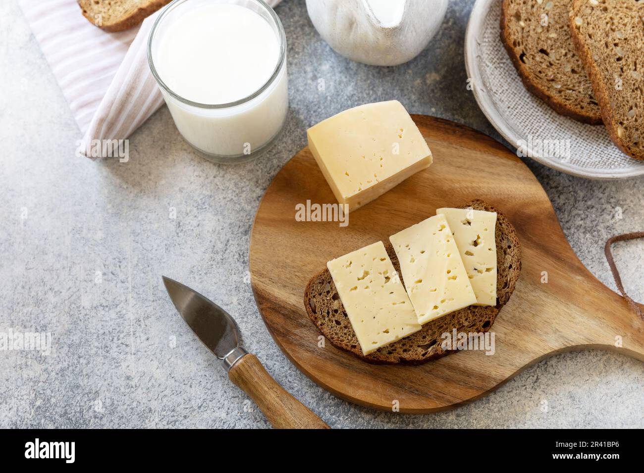 Konzept gesunder Speisen, Frühstück, Superfood. Frisches Vollkornbrot mit Käse und ein Glas Mandelmilch auf einem Steintisch. Verstanden Stockfoto