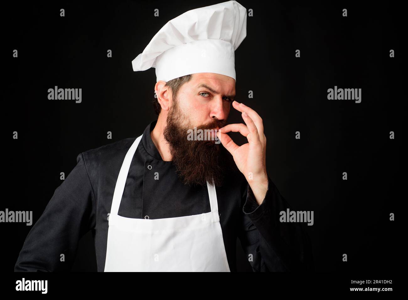 Professioneller männlicher Koch mit Kochhut und perfektem Schild. Chefkoch mit Geschmacksbestätigung, unterschreiben Sie für Delicious. Restaurantwerbung. Koch in Uniform Stockfoto