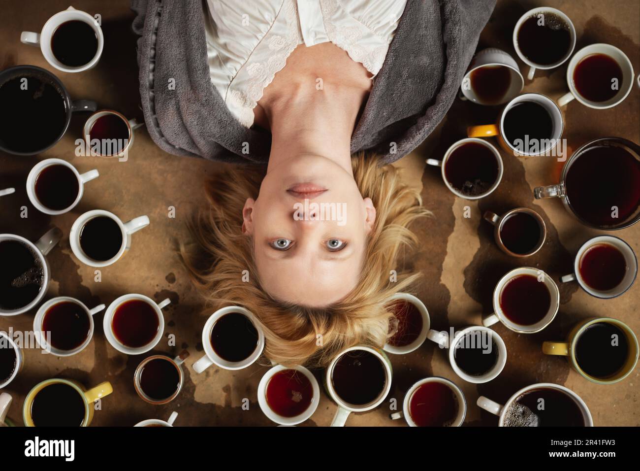 Schlaflose, wach Frau, umgeben von vielen Tassen Kaffee. Deadline, Schritt halten, in Form sein, Überstundenkonzept. Stockfoto
