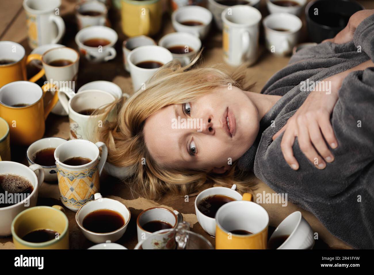 Schlaflose, wach Frau, umgeben von vielen Tassen Kaffee. Deadline, Schritt halten, in Form sein, Überstundenkonzept. Stockfoto