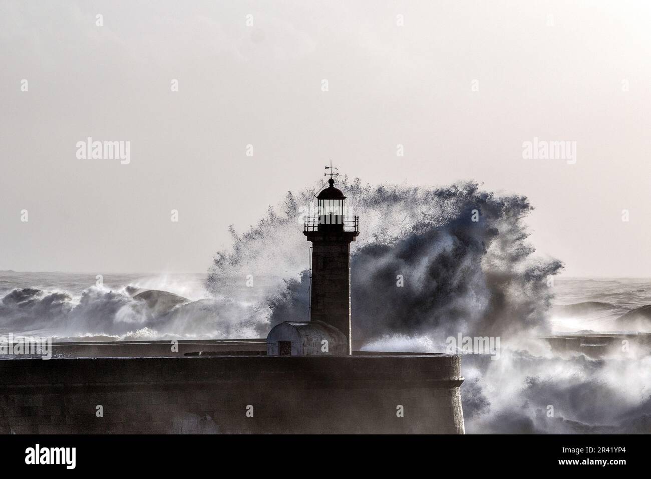 Wellen stürzen auf den alten Leuchtturm. Farolim de Felgueiras, Porto, Portugal. Stockfoto