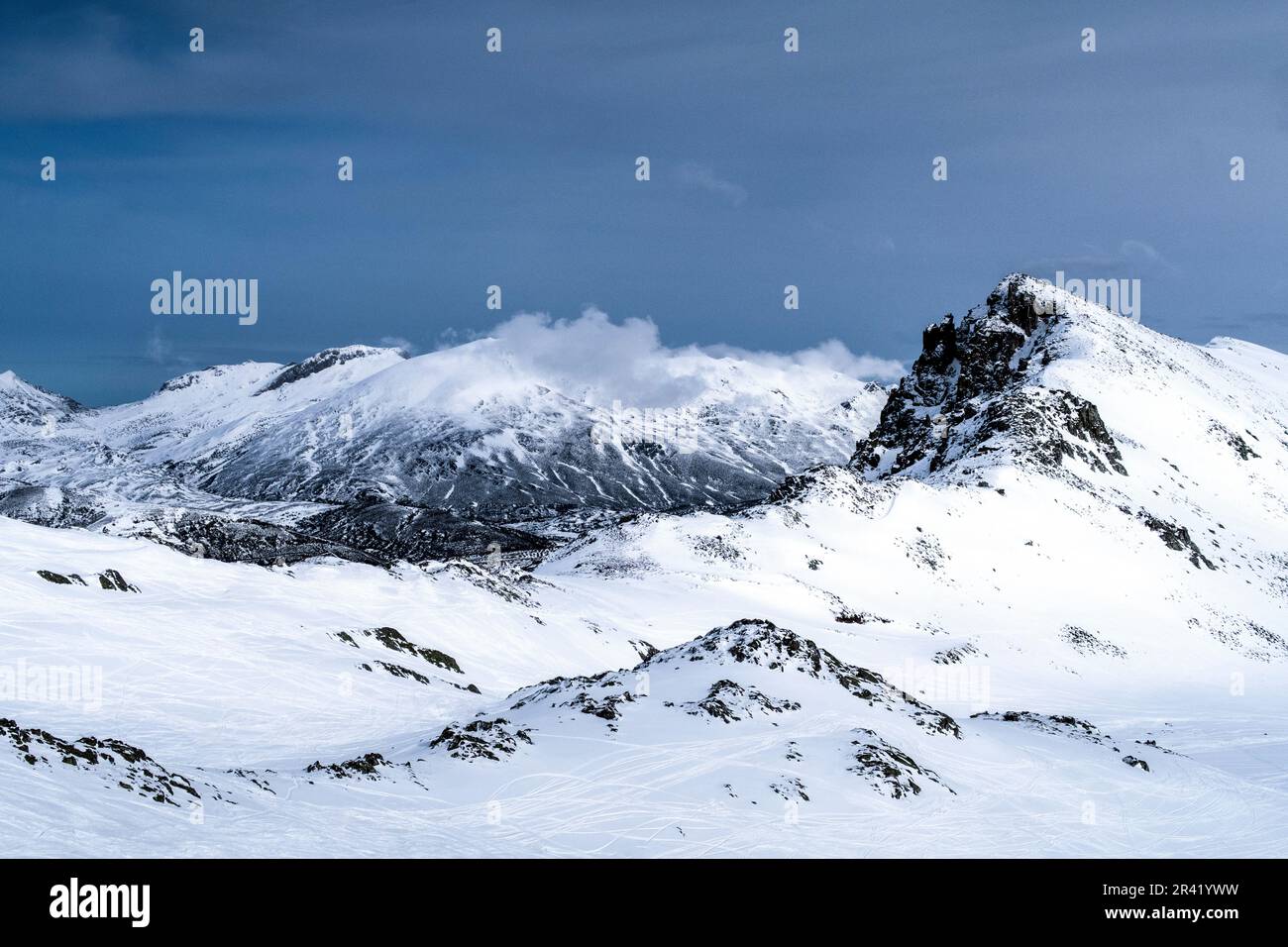 Schneebedeckte Berge unter einem bewölkten blauen Himmel Stockfoto
