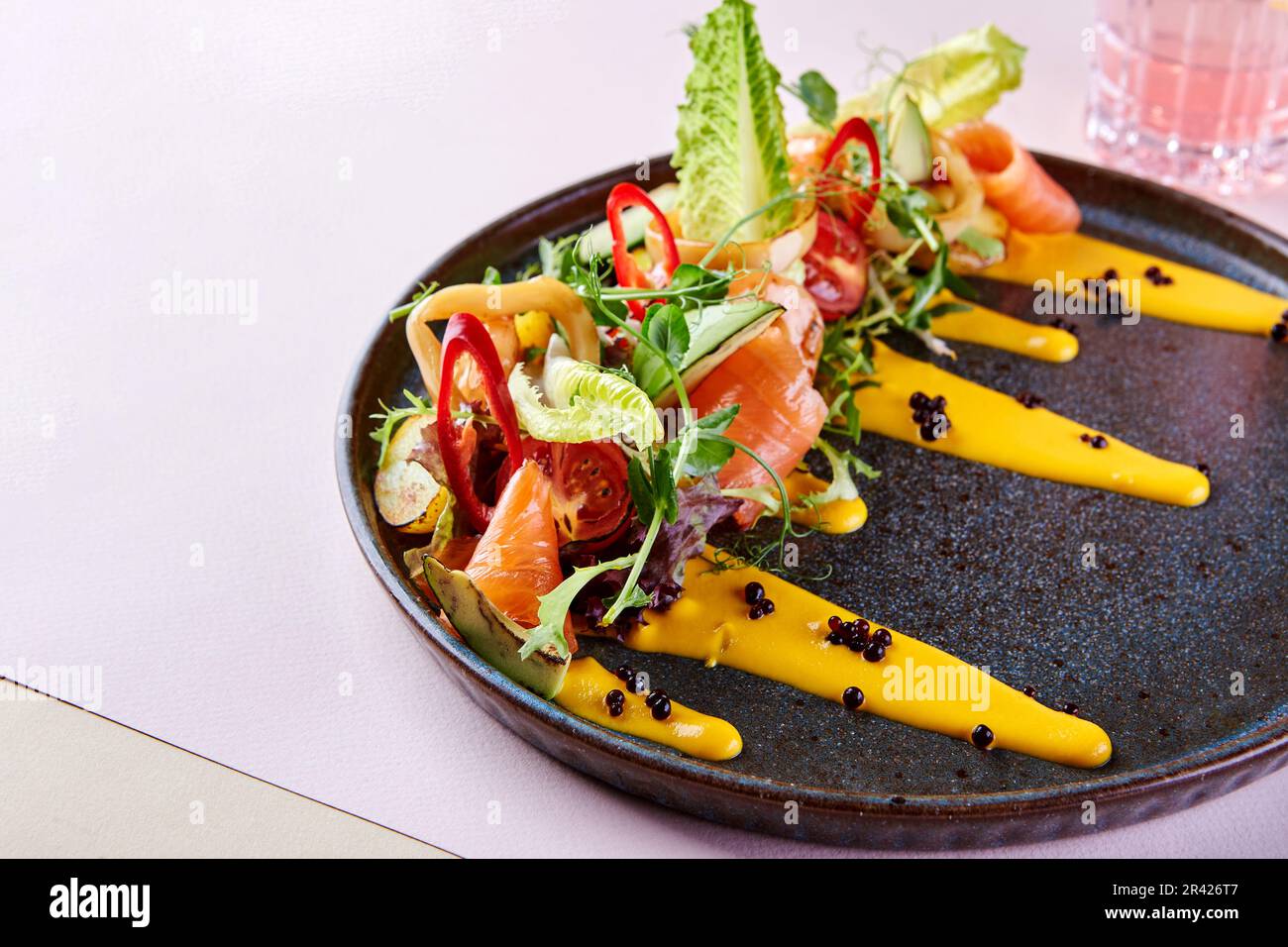 Wunderschönes Restaurant, das Gerichte mit rotem Fisch, Gemüse und Sauce serviert Stockfoto
