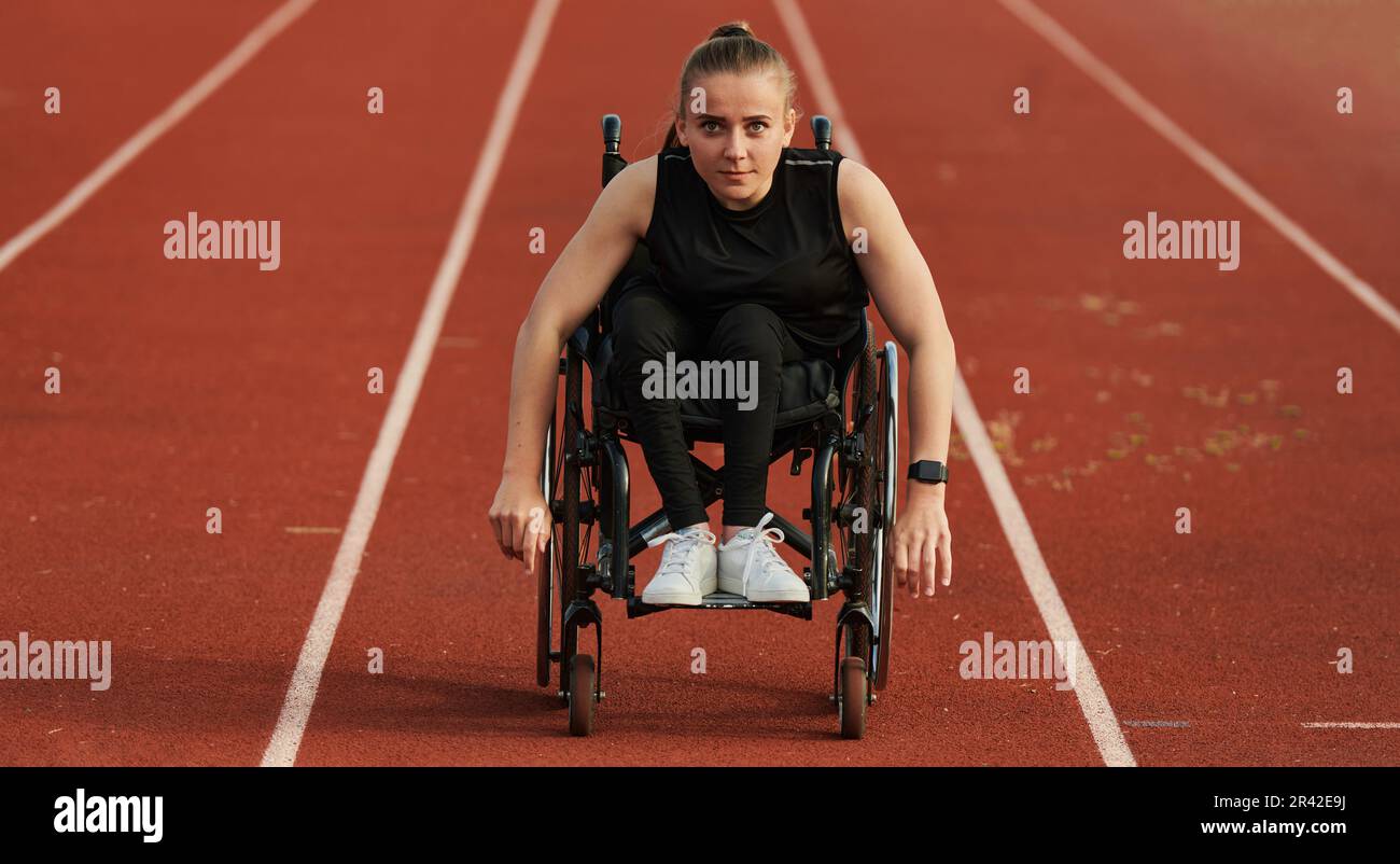 Eine behinderte Frau, die einen Rollstuhl auf einer Rennstrecke fährt, während sie sich auf die Paralympischen Spiele vorbereitet Stockfoto