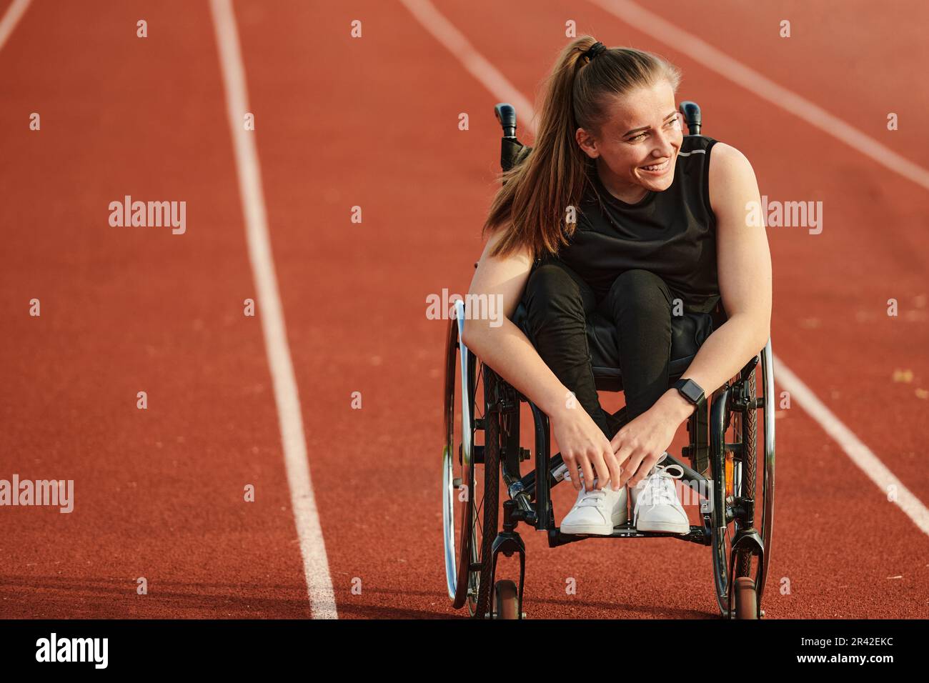 Eine behinderte Frau, die einen Rollstuhl auf einer Rennstrecke fährt, während sie sich auf die Paralympischen Spiele vorbereitet Stockfoto