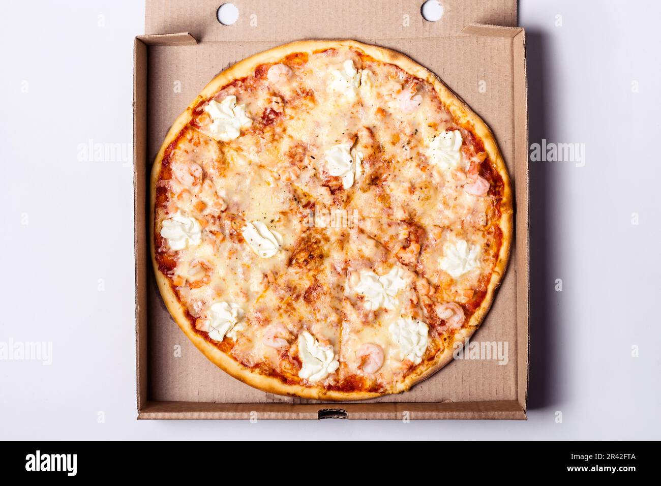 Pizza mit Meeresfrüchtegarnelen und Lachs in Packbox auf grauem Hintergrund Stockfoto