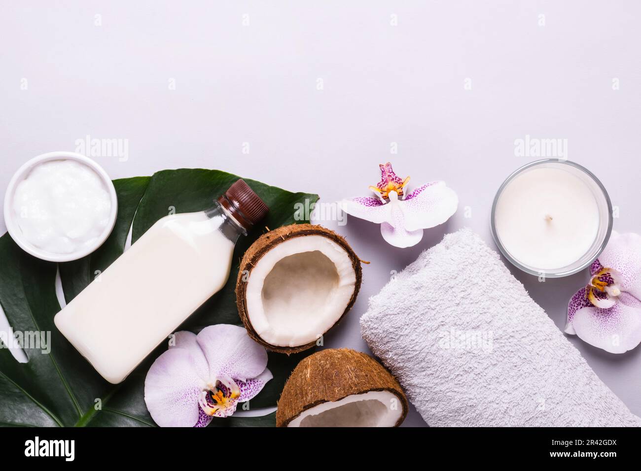 Kokosnuss-Kosmetikprodukt, tropische Blätter und Blumen. Natürliches Spa-Konzept Stockfoto