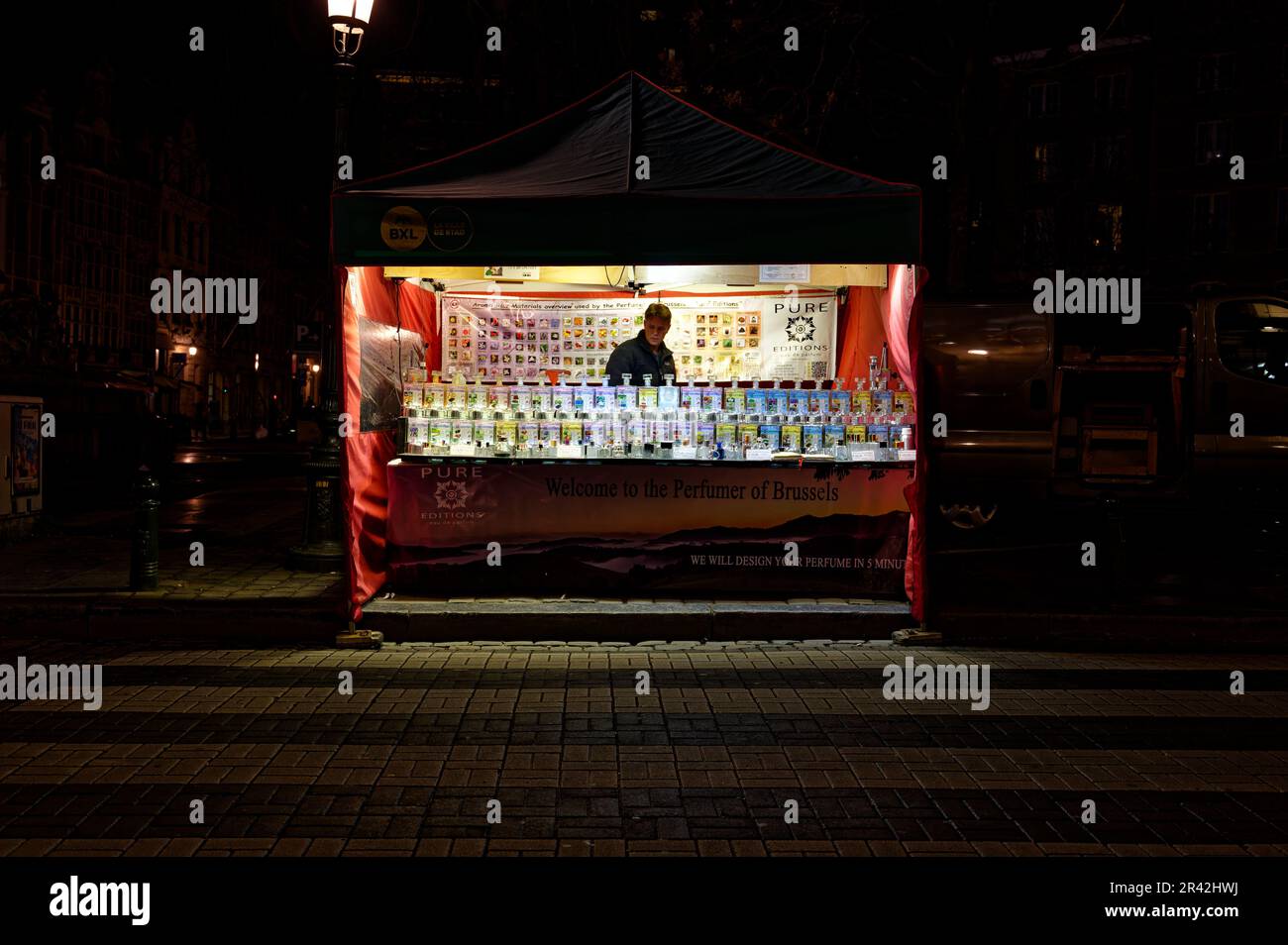Parfümmacher in seinem gut beleuchteten Stand in den Straßen von Brüssel. Einsamer Parfümdesigner, der auf Kunden wartet. Stockfoto