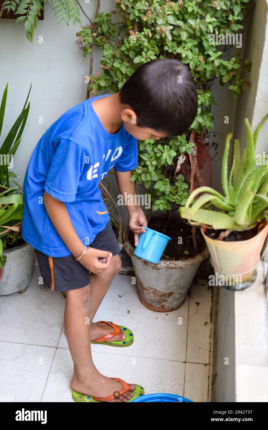Der süße 5 Jahre alte asiatische Junge gießt die Pflanze in den Töpfen auf dem Balkon des Hauses, Liebe des süßen kleinen Jungen für die Mutter Natur während w Stockfoto