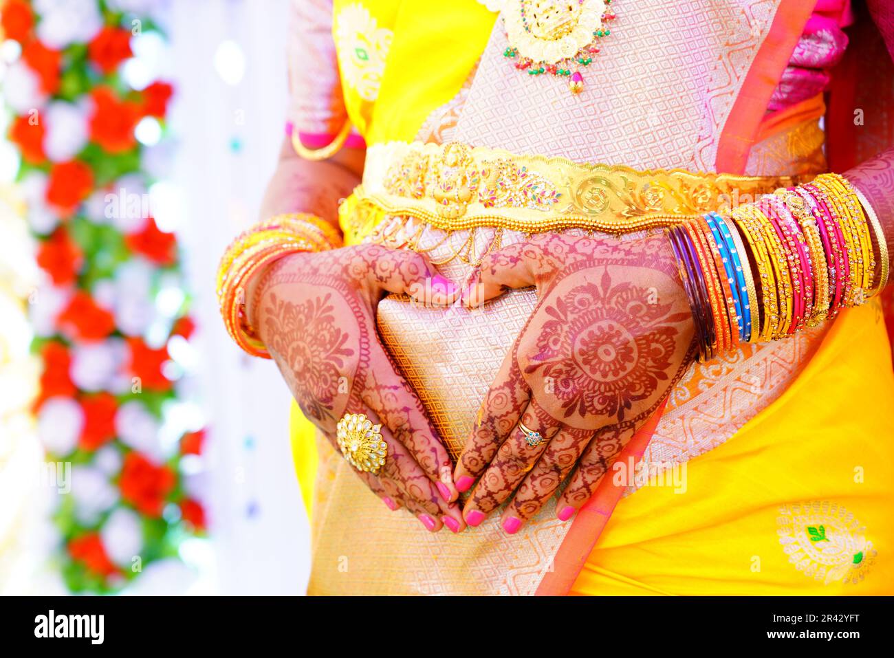 Eine Frau in einem gelben Saree hält ihre Hände in Form ihres Herzens Stockfoto