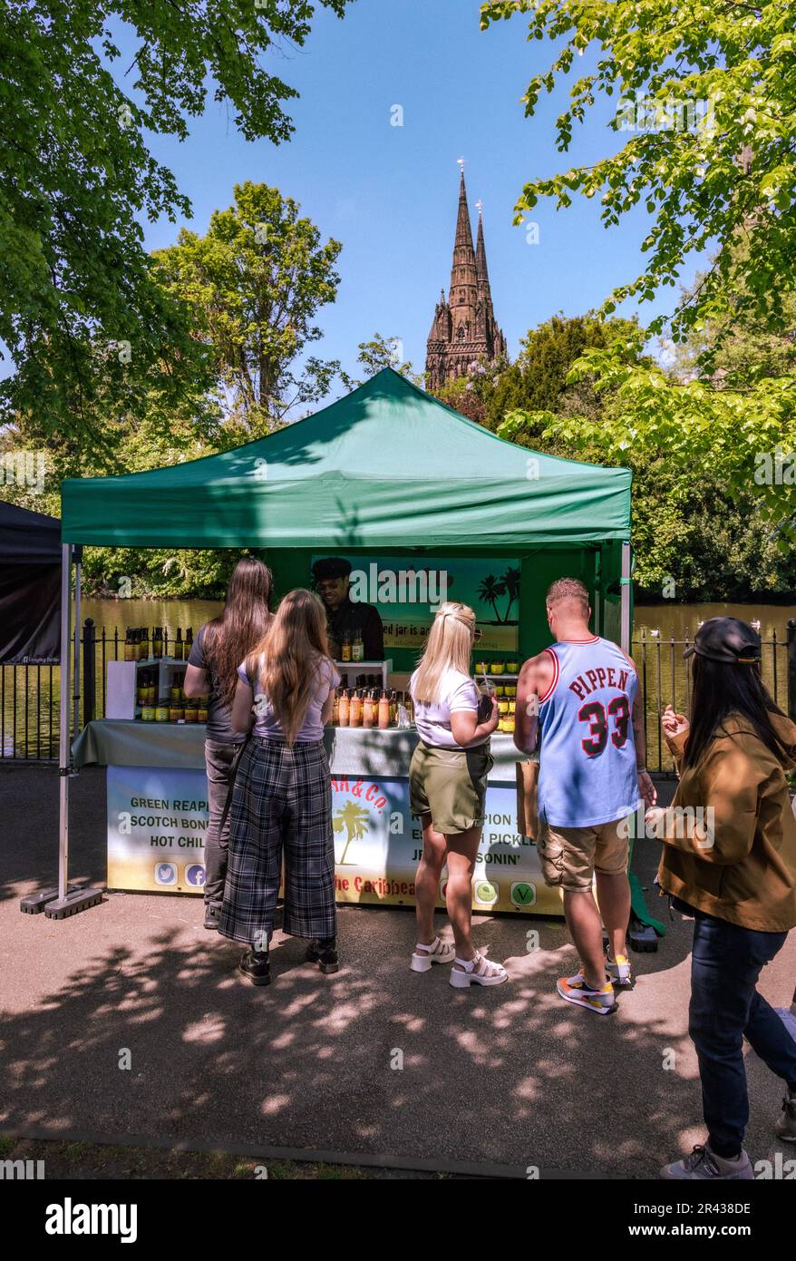 Die Leute versammeln sich beim Lichfield Food Festival an einem Stand. Die Kathedrale von Lichfield ist im Hintergrund zu sehen. Stockfoto